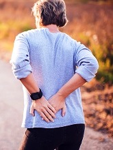lady in Cardiff holding her back with severe  lower back pain