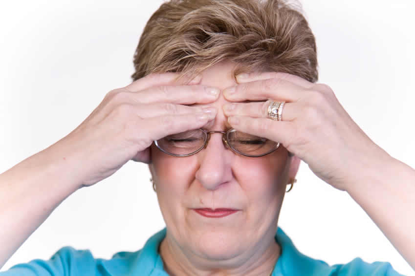lady holding her head due to migraine pain and headache seeking treatment in Cardiff